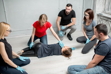 Young woman instructor showing how to lay down a woman during the first medical aid training indoors