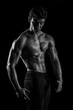 © abdulrahman - Highly retouched black and white fitness model and bodybuilder, Looking and posing abs and chest. concept of power and strength. black background.