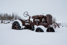 An Old Rusty Tractor Standing Alone In Snow, Reykjavik, Iceland