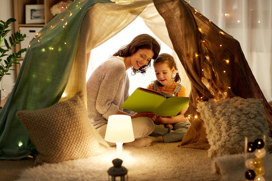happy family reading book in kids tent at home