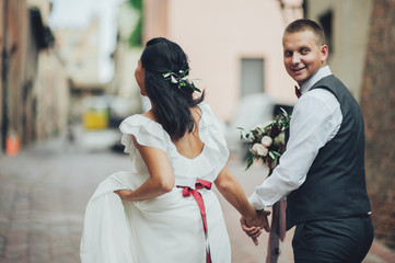 Wall Mural - Happy bride and groom walking in an old Italian village