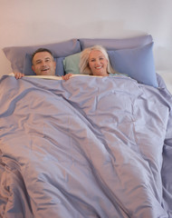 Wall Mural - Senior couple under blanket in bed together