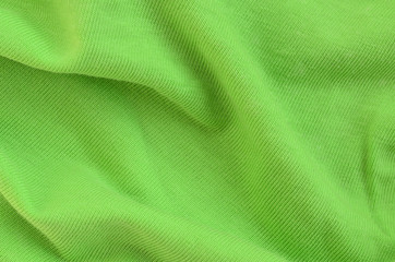 The texture of the fabric is bright green. Material for making shirts and blouses