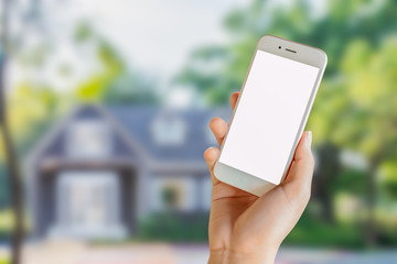 woman's hand holding mobile phone with blurred house in background, idea concept for property busine