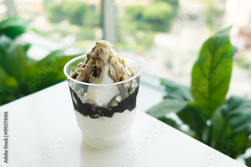 Zdjęcie XXL Lody Sundae z czekoladą i orzechem włoskim na plastikowym szkle na bielu stole