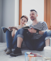 Wall Mural - Portrait happy smiling young couple painting interior wall of new house. Young couple