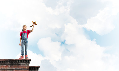 Concept of careless happy childhood with girl dreaming to become pilot