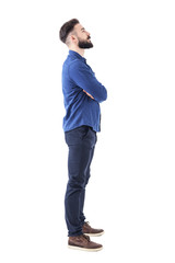 smart casual bearded business man with crossed arms looking up above. full body portrait isolated on