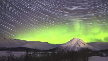 Wall Mural - Cumulative Time Lapse of Night Starry Sky with Star Trails and Green Northern Lights in Snowy Mountains at Winter Night
