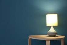 Elegant Lamp On Table Near Color Wall