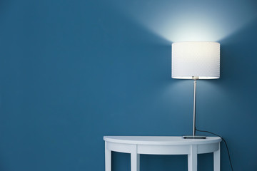 Wall Mural - Elegant lamp on table near color wall