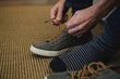 © Wavebreak Media - Man tying shoelaces in living room at home