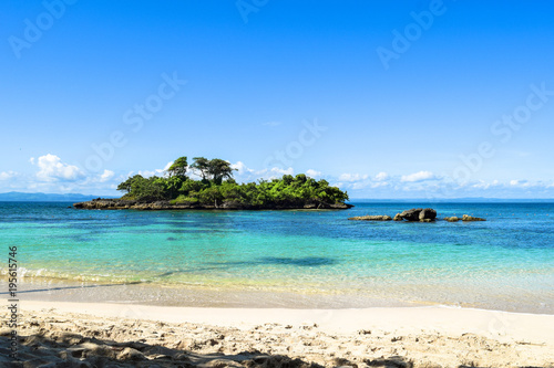 Fotomural White sandy beach, view over the blue turquoise water to a little island in the