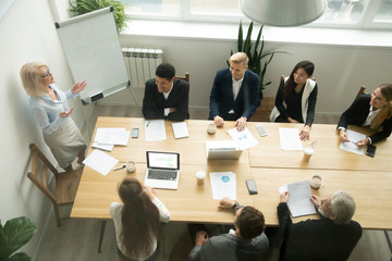 Poster - Aged senior businesswoman giving presentation at multiracial group office meeting, female team leader, company boss or business coach presenting corporate plan to executives in boardroom, top view