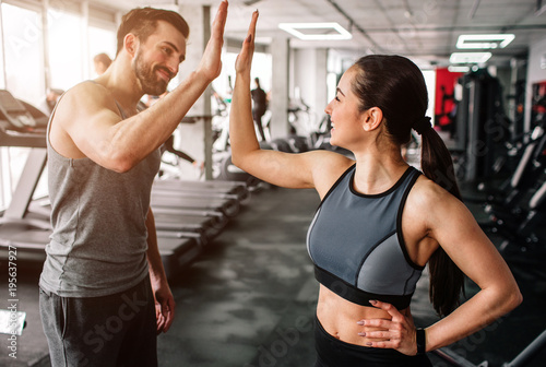 Fotografia A beautiful girl and her well-built boyfriend are greeting each other with a high-five