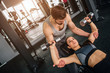 © estradaanton - Handsome guy standing near his girlfriend and helping her to do exersices with a dumbbell. He is supporting her to make sure she will not harm heerself.