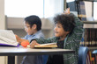 © Nattanon - Happy children in Learning Class at Library. Boy raised hand up his hand to answer a question from teacher. Setup studio shooting.