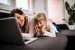 © bnenin - Cute little girl and her mother watching cartoons in the living room.