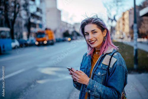 Cute Girl With Dyed Hair Standing On A Street Using Phone