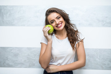 Beautiful woman giving bite to green apple at home