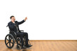 The man in a wheelchair phones and gestures on the white wall background