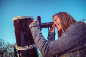 Wall Mural - cute young woman holding astronomical telescope and looking at the sky.