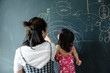 © MaaHoo Studio/Stocksy - Toddler girl with her mother drawing on blackboard wall