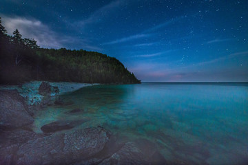 milky way and starry sky with wispy clouds along the lakeshore of georgian bay at night