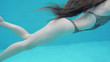 © Alice Nerr/Stocksy - torso, legs and long hair of woman swimming underwater in the sw