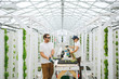 © Rob and Julia Campbell/Stocksy - Young sustainable farmers enjoying work in the greenhouse