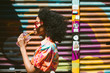 © Lauren Naefe/Stocksy - Young woman drinking juice against graffiti wall