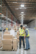 © Jetta Productions/Stocksy - Warehouse workers using cell phone