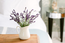 A White Jug Of Lavender Blooms In A Bedroom.