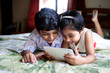 © Saptak Ganguly/Stocksy - Young boy and his younger sister busy with tablet