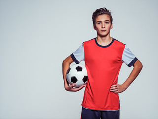 Photo of teen boy in sportswear holding soccer ball