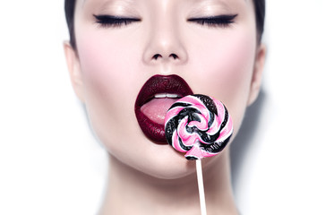Poster - Sexy beauty girl eating lollipop. Glamour model woman licking sweet colorful lollipop candy over white background