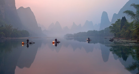 the li river, xingping, china, scenic landscape. cormorant fishermans on the ancient bamboo boats wi