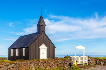 Budakirkja black painted lutheran parish erected in 1847 with blue sky and clouds in the background, Snaefellsnes Peninsula, West Iceland