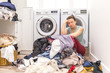 Sad woman sitting in laudry room with a pile of clothes