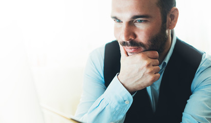 Bearded young businessman working on modern office at night. Consultant man thinking looking in monitor computer. Manager typing on keyboard in coworking workplace, startup project concept in studio