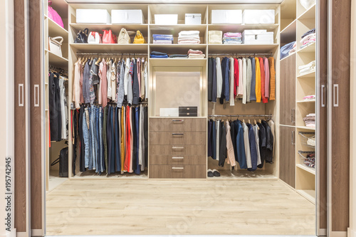 Fotografía Modern wooden wardrobe with clothes hanging on rail in walk in closet design int