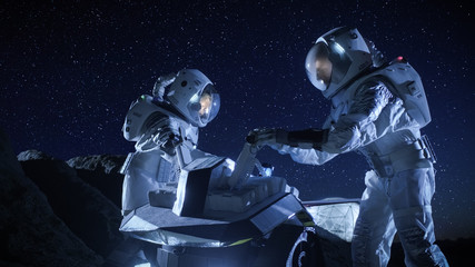 Wall Mural - two astronauts in space suits on an alien planet prepare space rover for surface exploration mission