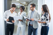 © Bojan - Group of business people discussing documents together in office hallway.