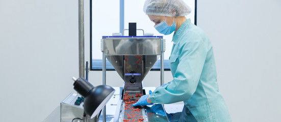 Wall Mural - Pharmacy industry woman worker in protective clothing operating production of tablets in sterile working conditions