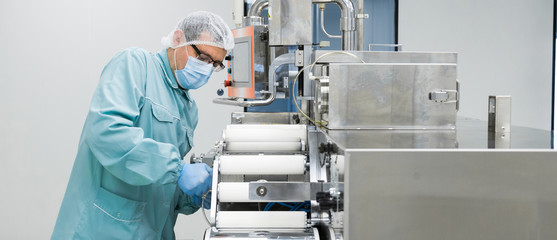 Canvas Print - Pharmacy industry factory man worker in protective clothing in sterile working conditions operating on pharmaceutical equipment