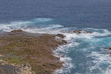 Canvas Print - Wave foam on the rocky coastline.