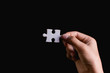 Hand holding piece of blank jigsaw puzzle