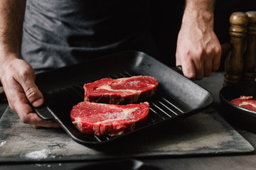 Sticker - Man cooking beef steaks Male hands holding a grill pan with beef steaks on kitchen