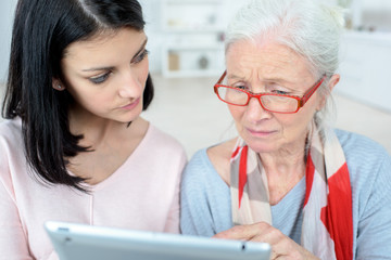 mother and daughter wiht tablet at sofa