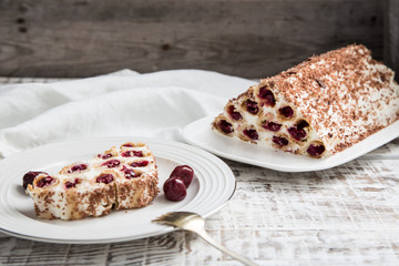 Wall Mural - cake with cherries, cream and chocolate on a light wooden background